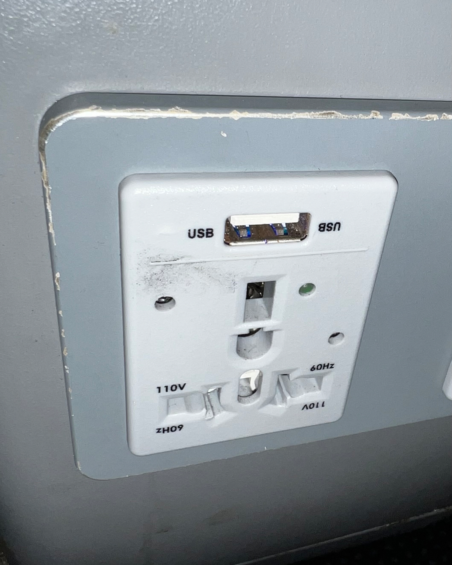 A power outlet with dual USB ports and a standard plug socket is mounted on a wall.